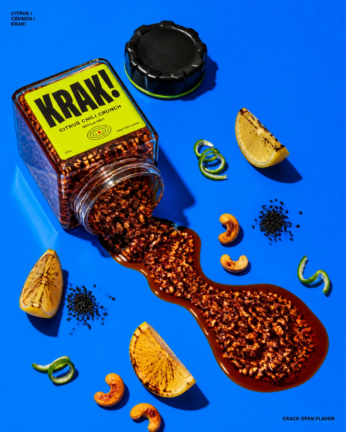Frasco de KRAK! derramando chili crunch sobre una superficie azul intensa